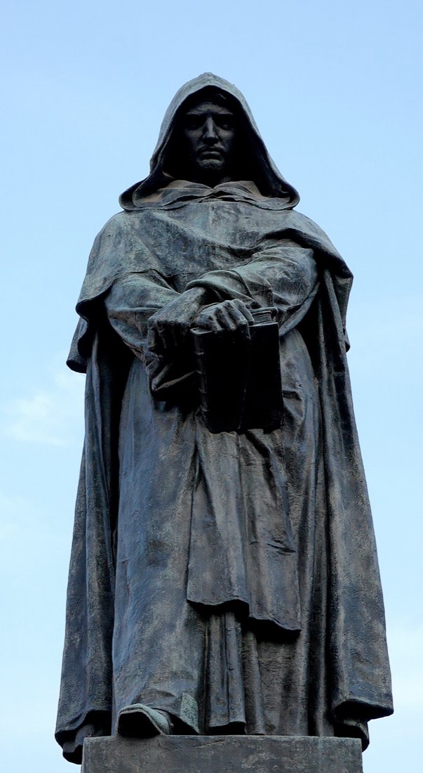 The bronze statue of Giordano Bruno, hooded and holding a book, against a pale sky